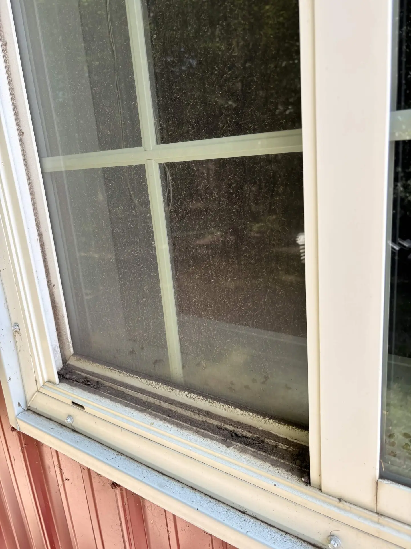 Window with grimy glass and a dirt-caked sill before cleaning